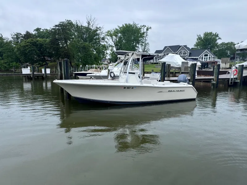 Slide: The Image of 2011 Sea Hunt Triton 225 boat docked on calm water near waterfront homes. - 2