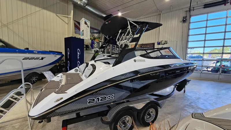 Slide: The Image of 2017 Yamaha Boats 212X in showroom, sleek black and white design on trailer. - 2