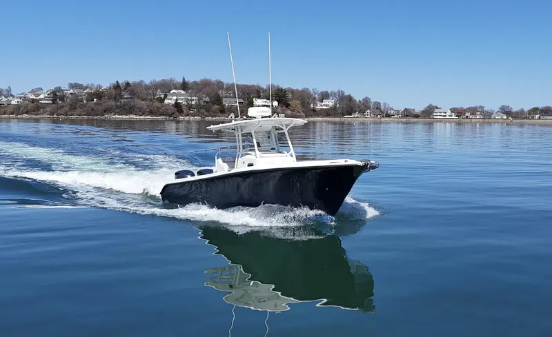 The Image of 2009 Edgewater 318CC boat cruising on calm water near a coastal landscape. - 0