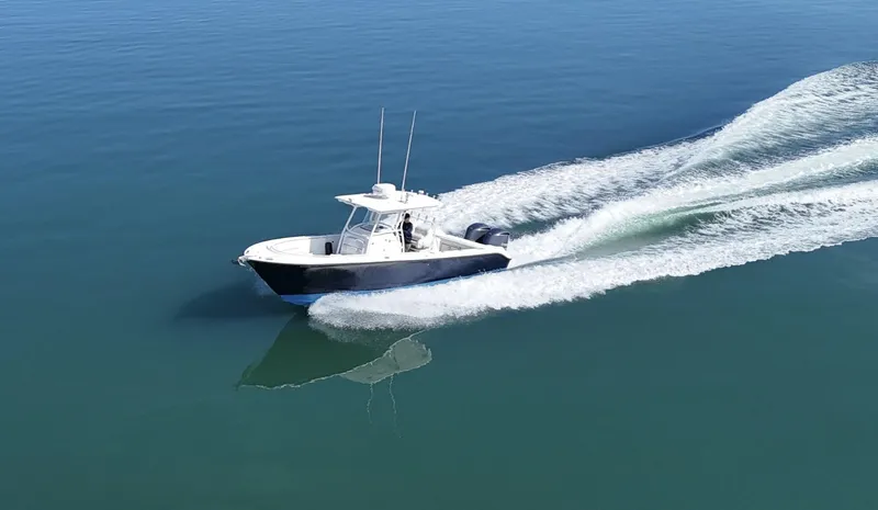 Slide: The Image of 2009 Edgewater 318CC boat cruising on calm blue water, creating a white wake. - 1