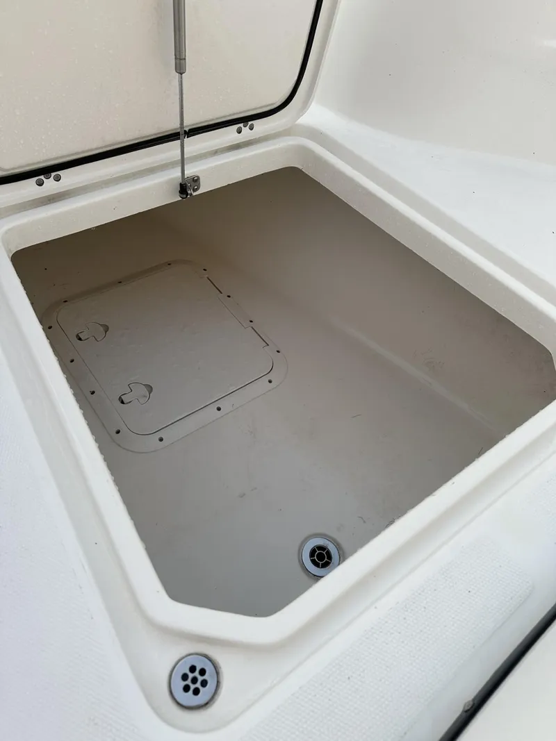 Slide: The Image of 2009 Edgewater 318CC boat storage compartment, open lid, white interior, drain holes visible. - 16