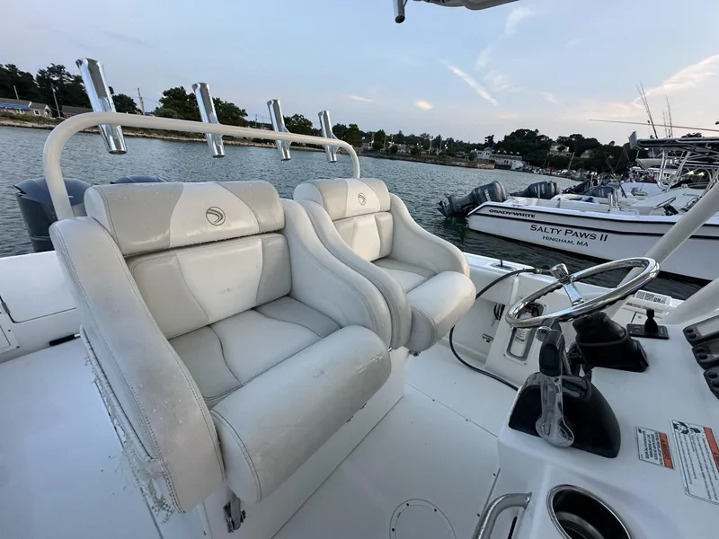 Slide: The Image of 2009 Edgewater 318CC boat with white seating, steering wheel, and docked boats in the background. - 20