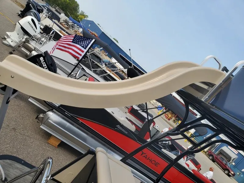 Slide: The Image of 2024 Avalon Catalina Entertainer Funship with slide, docked among other boats, American flag visible. - 11