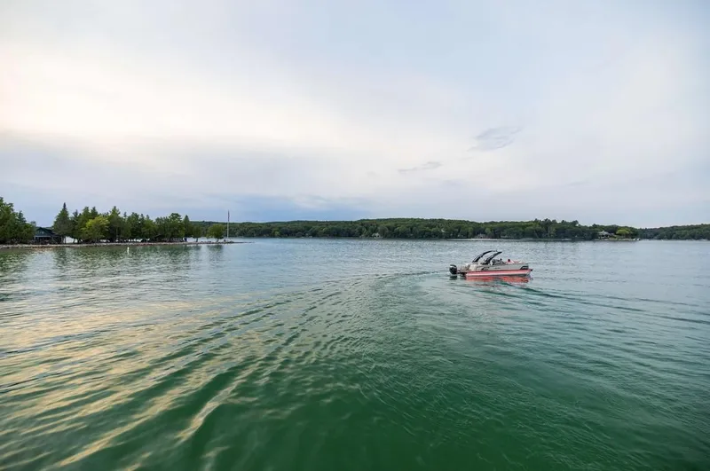 Slide: The Image of 2024 Avalon Excalibur LTD Elite Windshield boat cruising on a serene lake. - 11