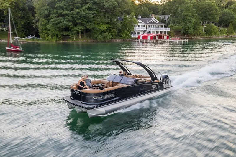 Slide: The Image of 2024 Avalon Excalibur LTD Elite Windshield cruising on a scenic lake near a lakeside house. - 4