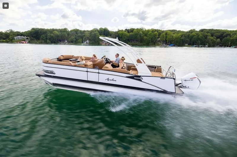 Slide: The Image of 2024 Avalon Excalibur LTD Elite Windshield boat cruising on a scenic lake. - 6