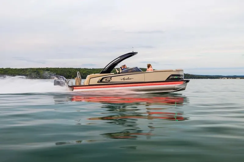 Slide: The Image of 2024 Avalon Excalibur LTD Elite Windshield boat speeding on a calm lake. - 9