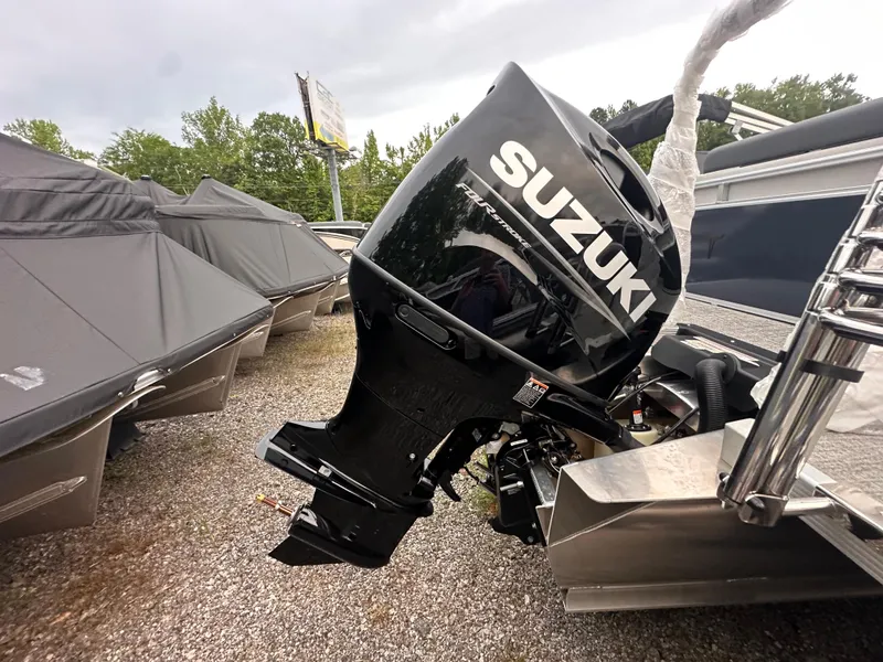 Slide: The Image of 2025 Tahoe Pontoon LTZ Versatile Rear Lounger with Suzuki outboard motor, parked outdoors. - 11