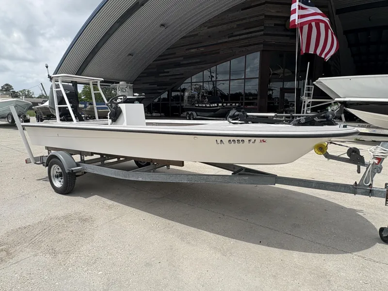 Slide: The Image of 2004 Custom Mitizi Skiff 17 boat on trailer, parked outside a building with an American flag. - 5
