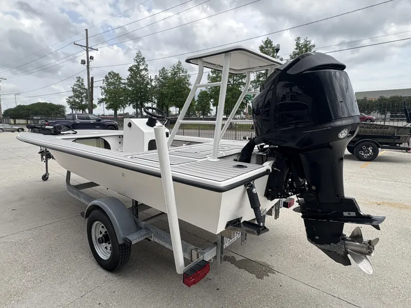Slide: The Image of 2004 Custom Mitizi Skiff 17 boat on trailer with outboard motor, parked outdoors. - 7