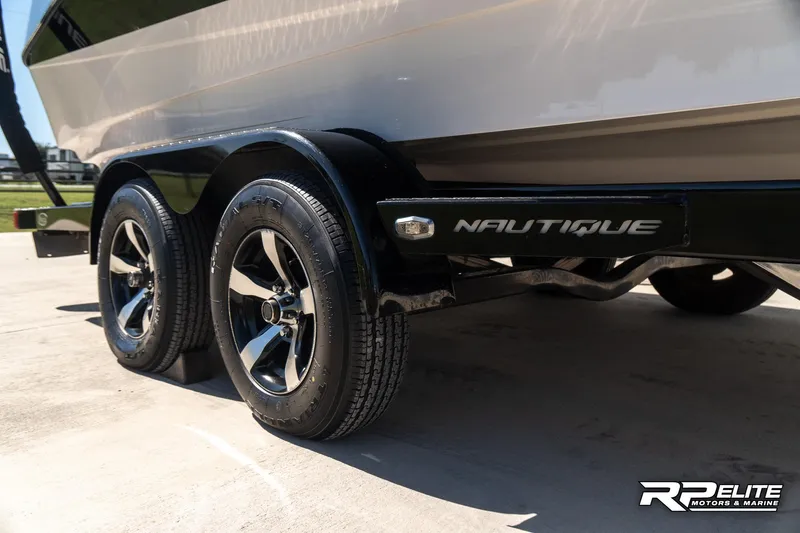 Slide: The Image of 2014 Nautique Super Air Nautique 230 trailer with dual axles and chrome wheels. - 15
