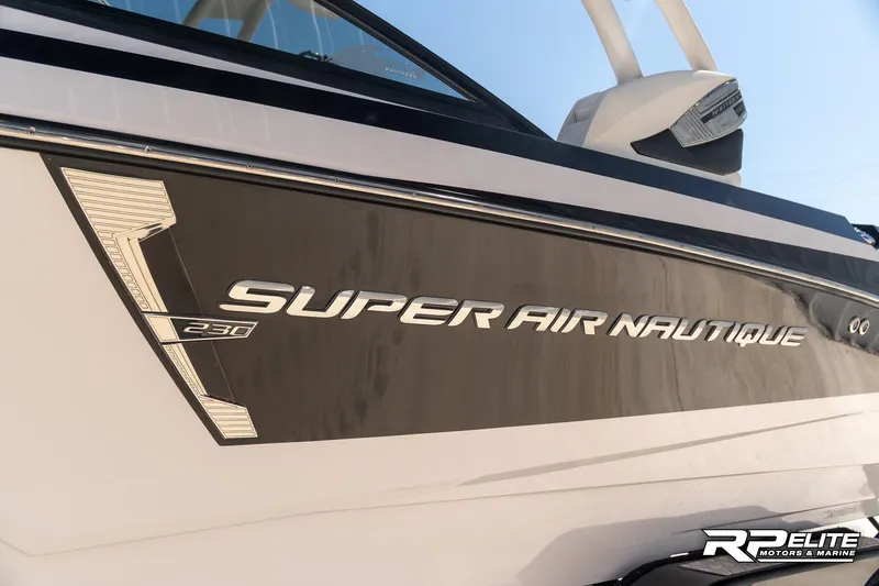 Slide: The Image of 2014 Nautique Super Air Nautique 230 boat side view with logo and branding. - 20