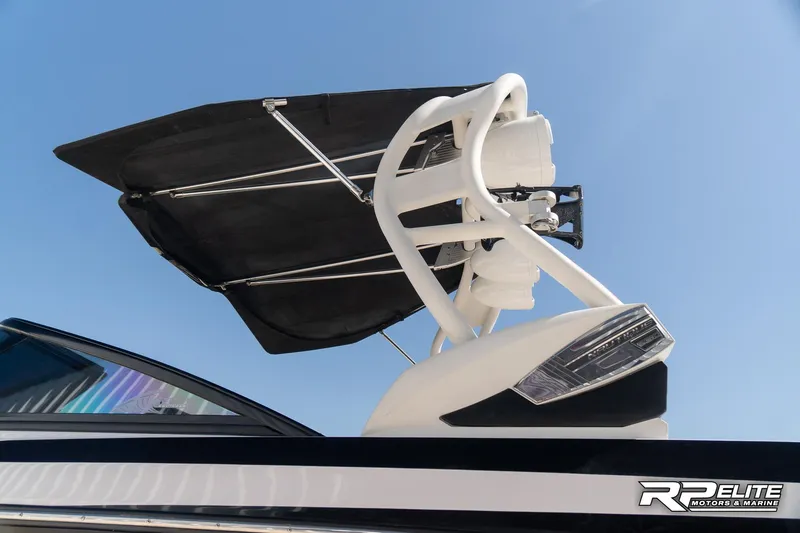 Slide: The Image of 2014 Nautique Super Air Nautique 230 boat with wakeboard tower and bimini top against blue sky. - 22