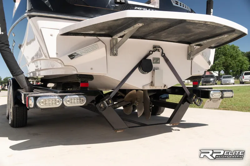 Slide: The Image of 2014 Nautique Super Air Nautique 230 boat rear view with propeller and trailer. - 25
