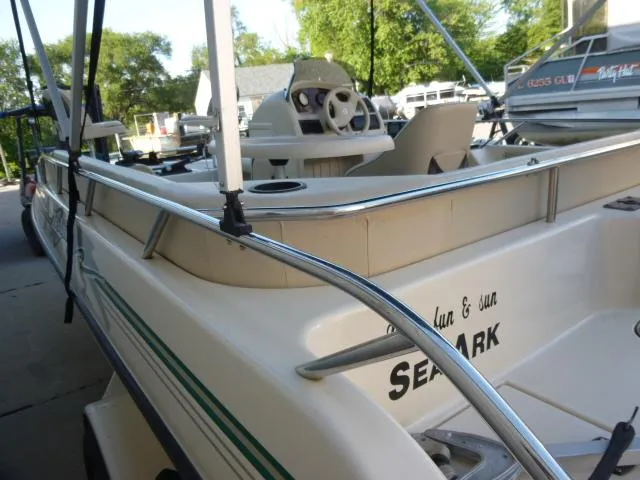 Slide: The Image of 2000 SeaArk Sunstar 21 boat with steering wheel and seating, docked outdoors. - 6