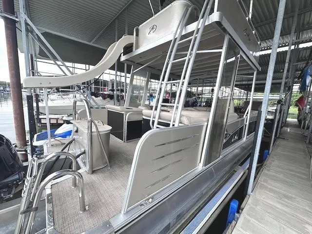 Slide: The Image of 2016 Tahoe Pontoon Vista Funship Entertainer with slide, docked under a covered marina. - 10