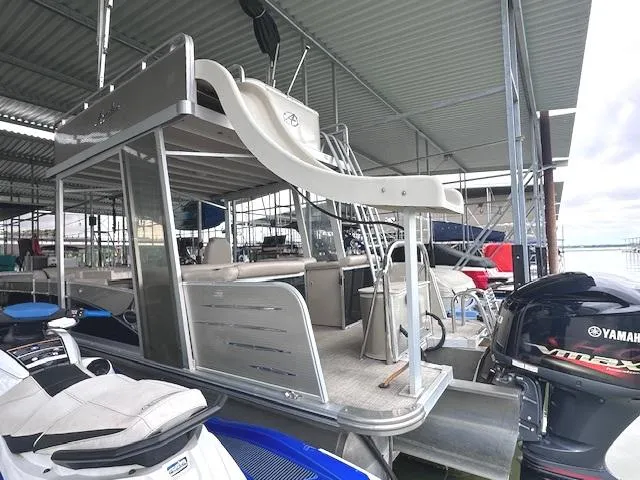 Slide: The Image of 2016 Tahoe Pontoon Vista Funship Entertainer with slide, docked under a metal canopy. - 11