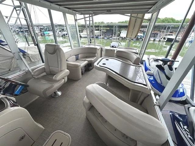 Slide: The Image of 2016 Tahoe Pontoon Vista Funship Entertainer interior with seating and table, docked at marina. - 15