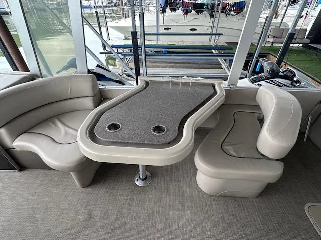 Slide: The Image of 2016 Tahoe Pontoon Vista Funship Entertainer interior with seating and table, docked at marina. - 17