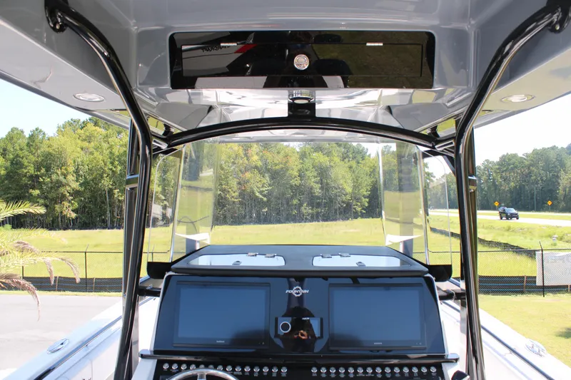 Slide: The Image of 2023 Fountain 34 CC boat dashboard with dual screens and scenic background. - 21