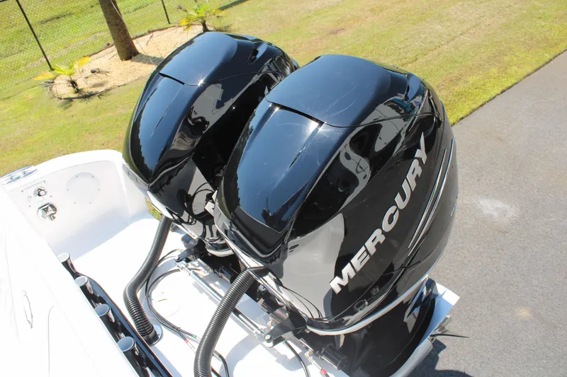 Slide: The Image of Twin Mercury outboard engines on a 2023 Fountain 34 CC boat, parked on grass. - 44