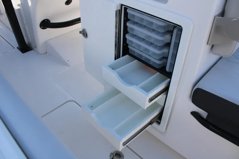 Slide: The Image of 2023 Fountain 34 CC boat storage compartment with open drawers and tackle boxes. - 49