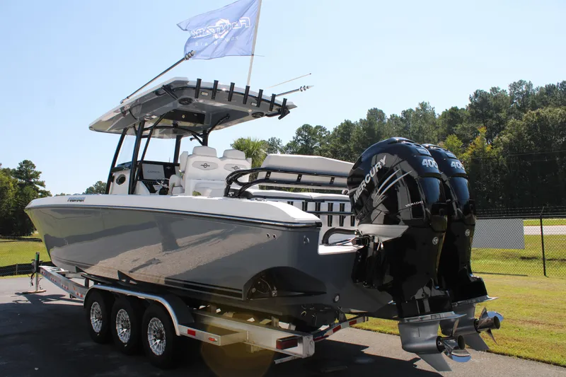 Slide: The Image of 2023 Fountain 34 CC boat on trailer with triple Mercury engines, parked outdoors. - 6