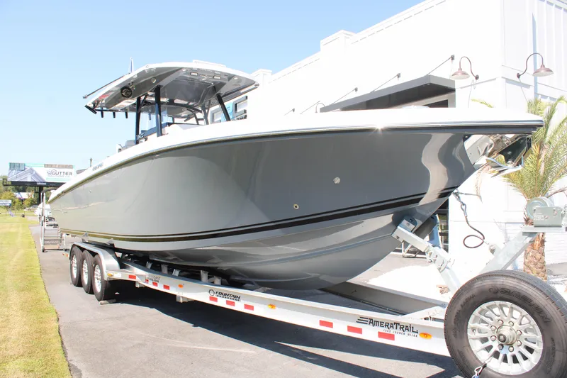 Slide: The Image of 2023 Fountain 34 CC boat on trailer, sleek design, parked outdoors. - 7