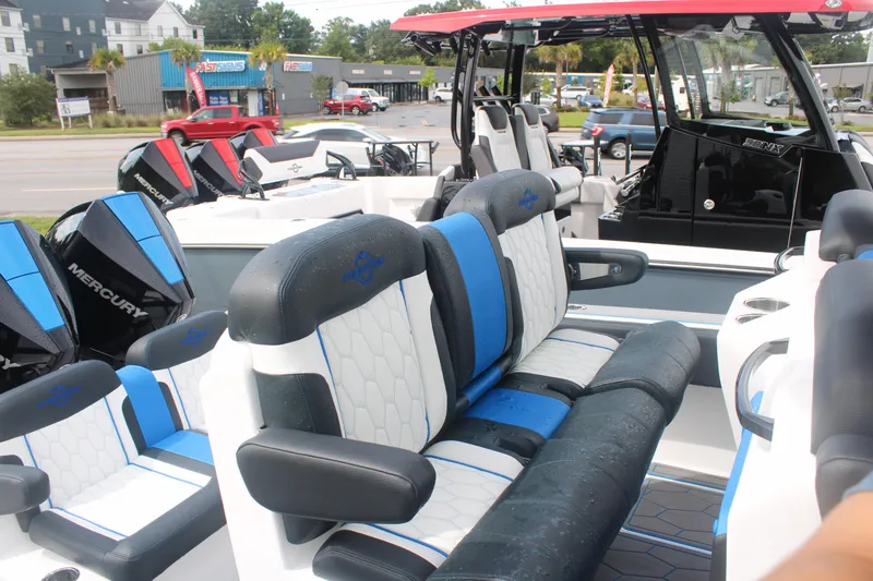 Slide: The Image of 2024 Fountain 34 SC boat interior with blue and white seating, parked outdoors. - 28