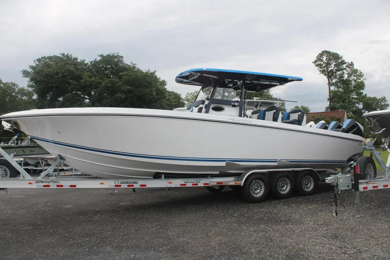 Slide: The Image of 2024 Fountain 34 SC boat on trailer, white hull, blue accents, parked outdoors. - 6