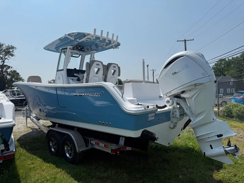 Slide: The Image of 2025 Sportsman Heritage 261 Center Console boat on trailer, blue hull, dual engines. - 2