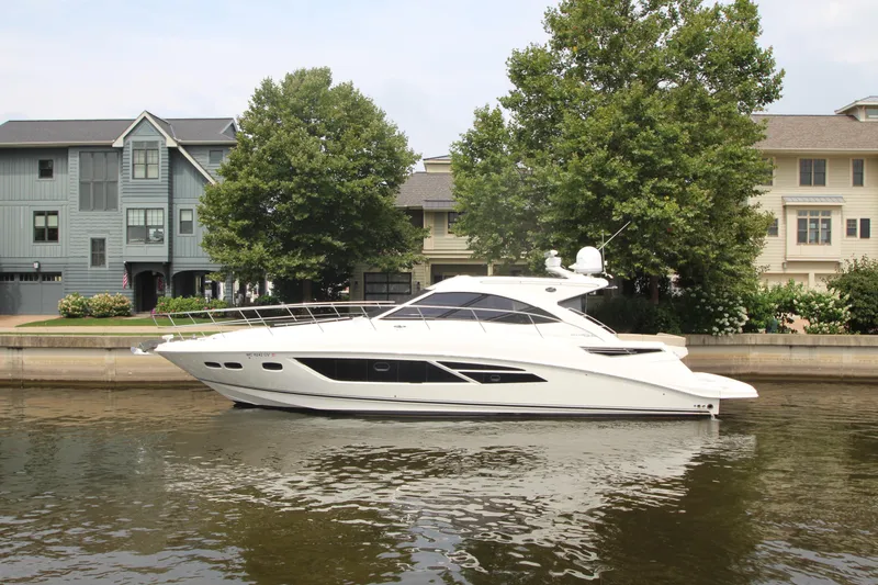 Slide: The Image of 2016 Sea Ray 510 Sundancer yacht docked by waterfront homes, surrounded by trees. - 10