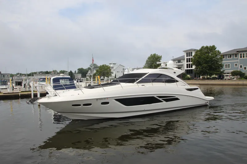 Slide: The Image of 2016 Sea Ray 510 Sundancer yacht docked in a marina, surrounded by buildings and trees. - 8