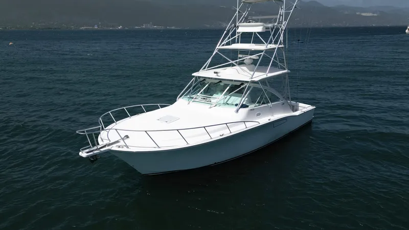 Slide: The Image of 2007 Cabo 40 Hardtop Express boat on calm water with mountainous background. - 11