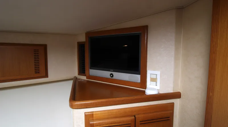 Slide: The Image of 2007 Cabo 40 Hardtop Express interior with mounted TV and wooden cabinetry. - 25
