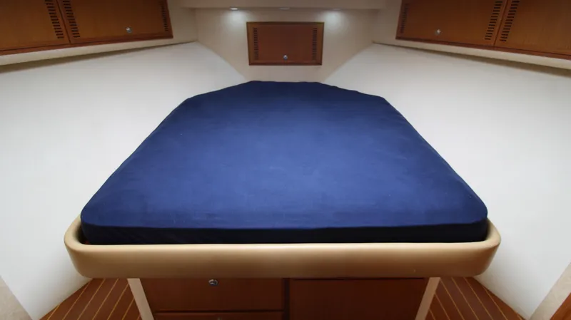 Slide: The Image of 2007 Cabo 40 Hardtop Express cabin with blue bed, wooden accents, and overhead lighting. - 28