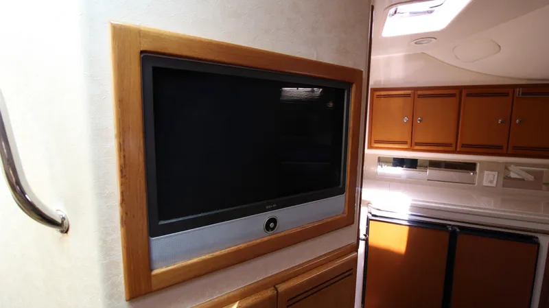 Slide: The Image of 2007 Cabo 40 Hardtop Express interior with mounted TV and wooden cabinetry. - 37