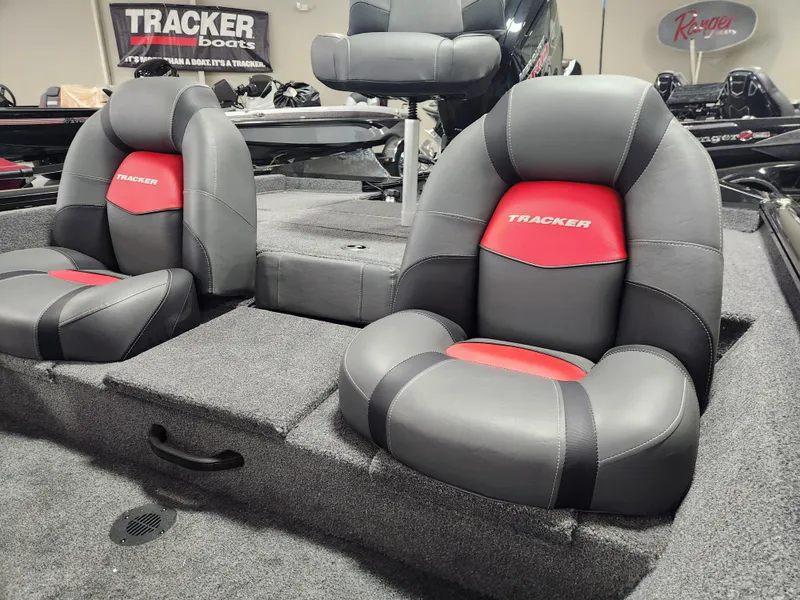 Slide: The Image of 2025 Tracker Pro Team 190 boat seats with red and black design in showroom. - 6
