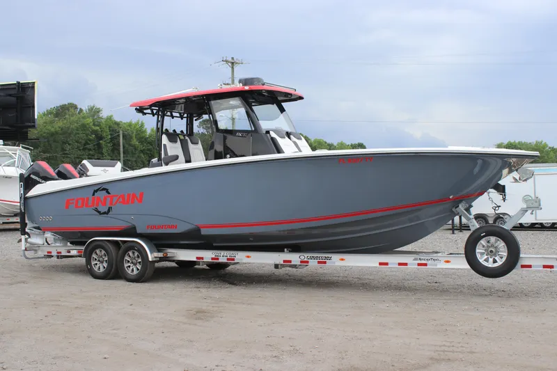 The Image of 2024 Fountain 32 NX boat on trailer, gray with red accents, parked outdoors. - 0
