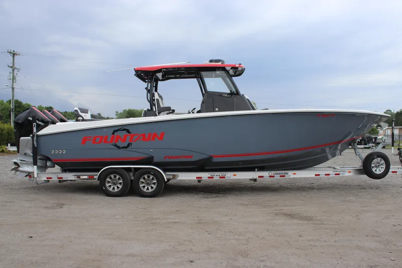 Slide: The Image of 2024 Fountain 32 NX boat on trailer, gray with red accents, parked outdoors. - 3
