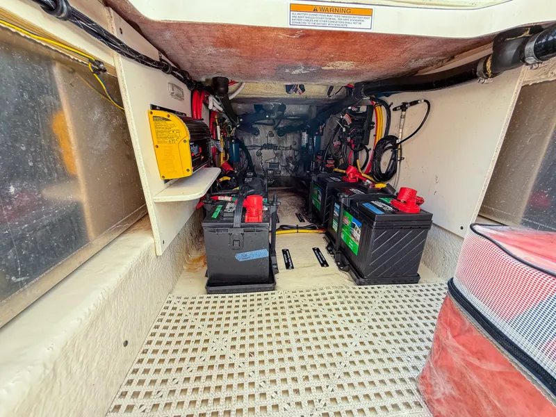 Slide: The Image of 2020 Robalo R317 Dual Console boat battery compartment with multiple batteries and wiring. - 21