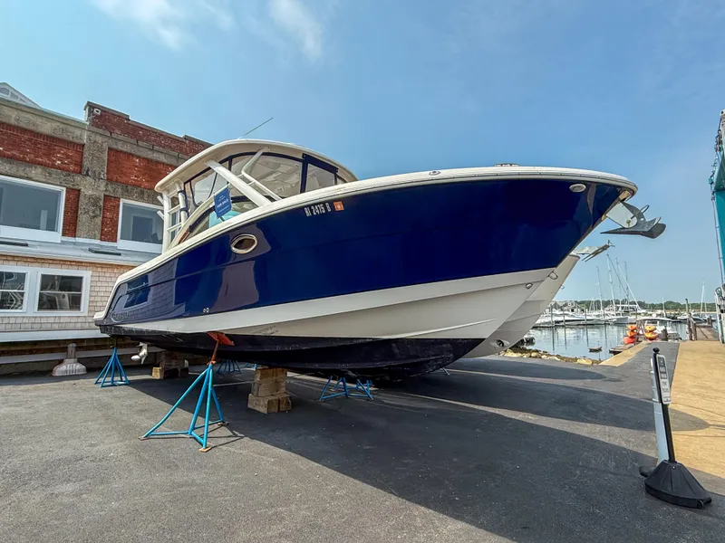 Slide: The Image of 2020 Robalo R317 Dual Console boat on stands, dockside, with blue and white hull. - 22