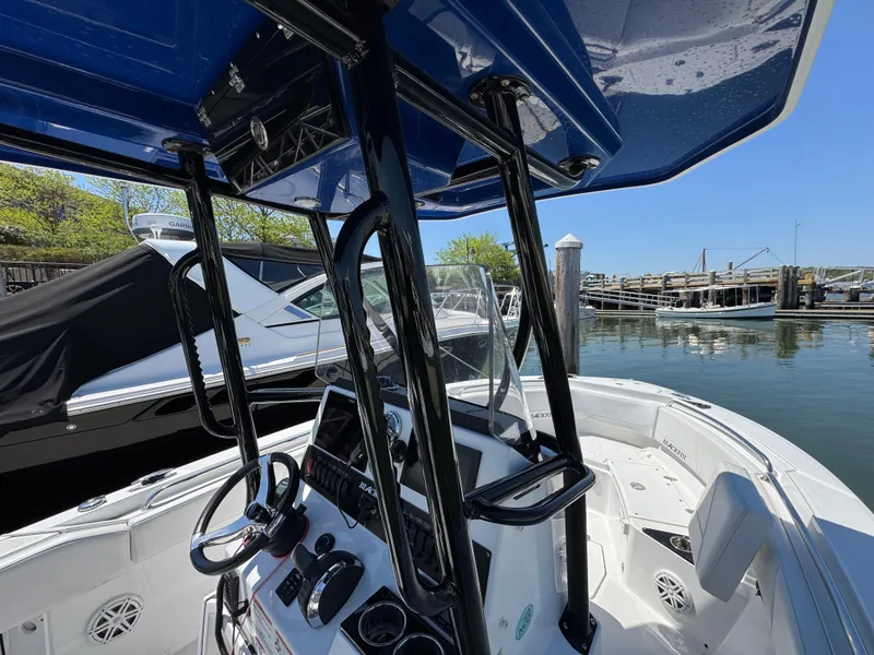 Slide: The Image of 2020 Blackfin 212 CC boat interior at marina, featuring steering console and blue canopy. - 27