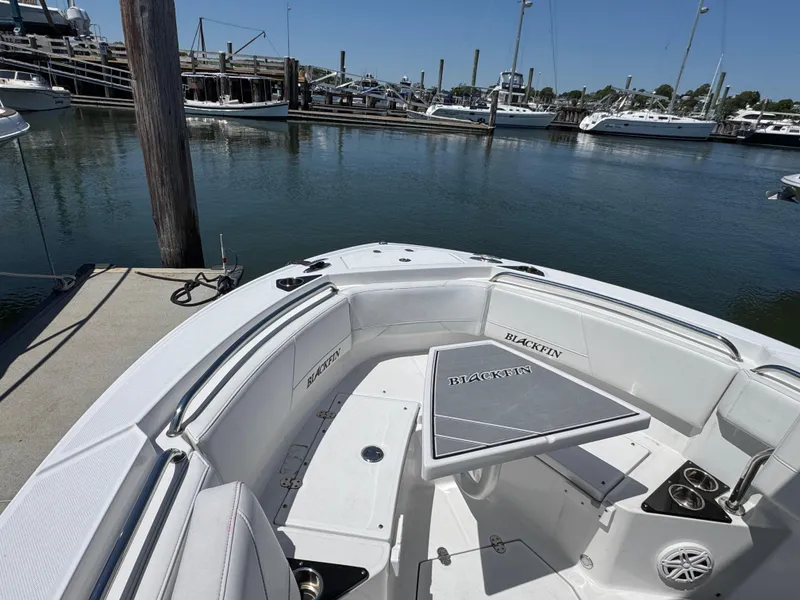 Slide: The Image of 2020 Blackfin 212 CC boat docked at marina, featuring spacious seating and table. - 33