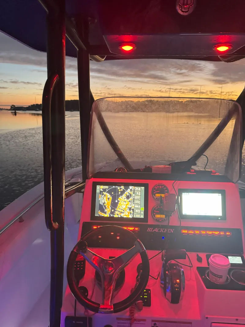 Slide: The Image of 2020 Blackfin 212 CC boat dashboard at sunset with navigation screens and red lighting. - 38