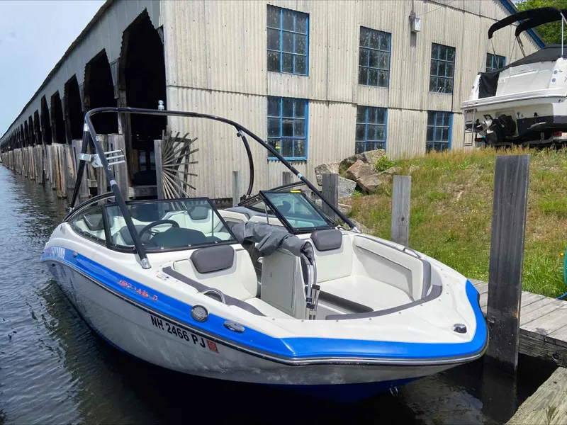 Slide: The Image of 2015 Yamaha Boats AR192 docked near a rustic boathouse. - 2