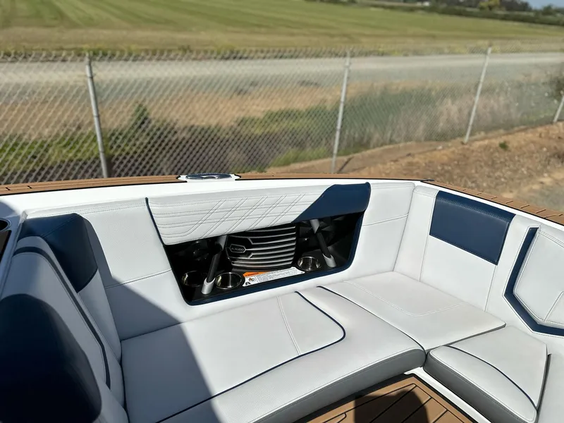 Slide: The Image of 2019 Nautique Super Air G23 boat interior with white and blue seating, near a fence and field. - 19