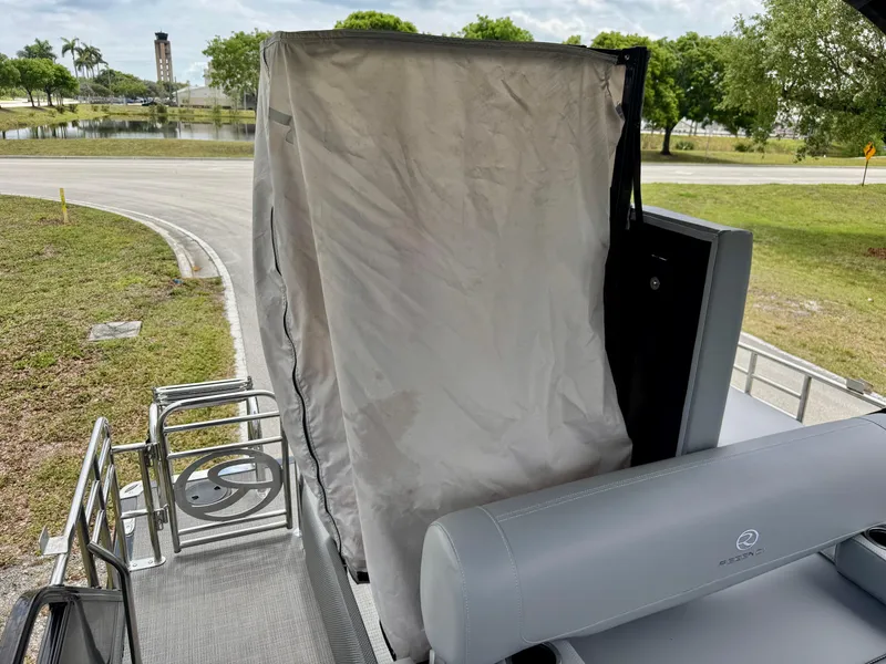 Slide: The Image of 2022 Regency 230 LE3 boat with covered seating area, parked near a lake. - 25