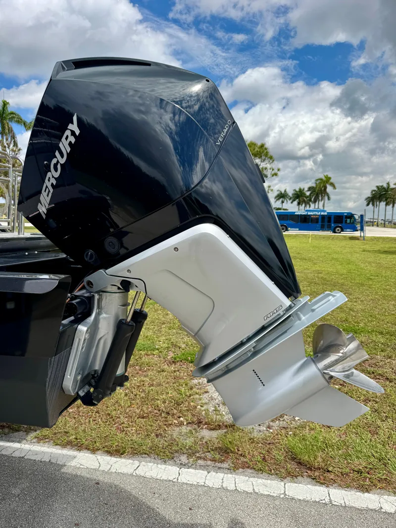 Slide: The Image of 2022 Regency 230 LE3 boat with Mercury outboard motor, parked outdoors under a cloudy sky. - 28