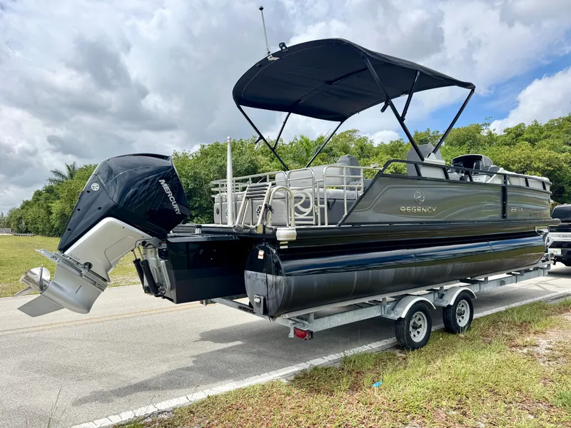Slide: The Image of 2022 Regency 230 LE3 pontoon boat on trailer, featuring a Mercury outboard motor. - 4